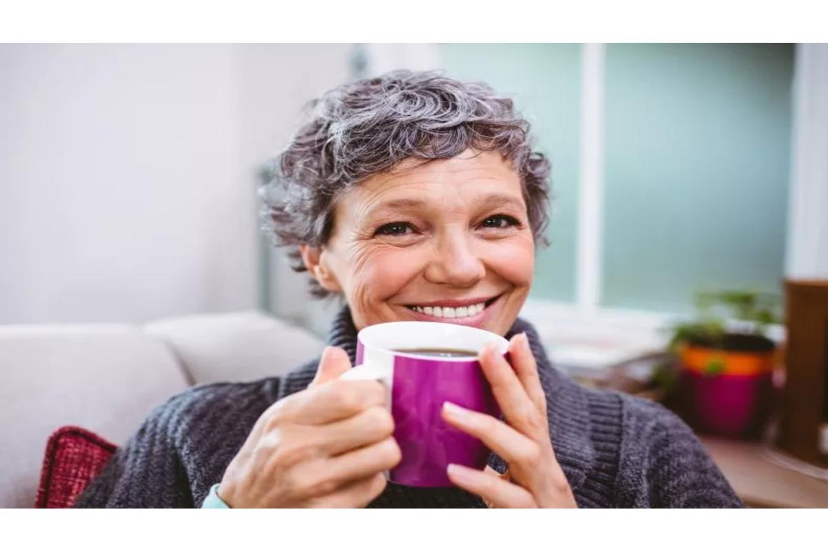 Tazza di caffè fumante su tavolo, simbolo di benessere e invecchiamento sano per le donne.